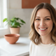 Close-up portrait of a smiling North American woman in her 30s, exuding warmth and trust in a soft-lit kitchen.